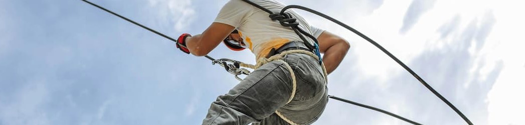 A man wearing a body harness and safety helmet attached to a safety line