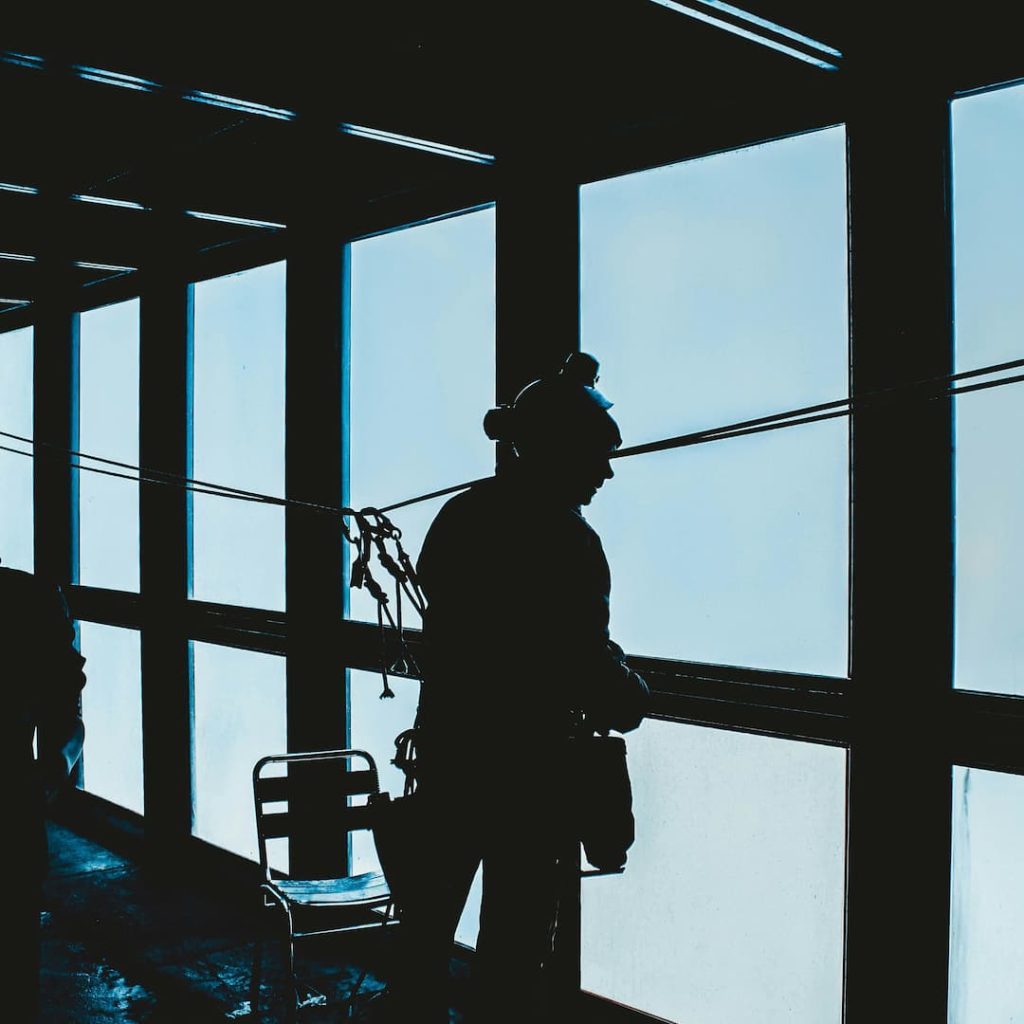 Male connected to a safety line looking out of window