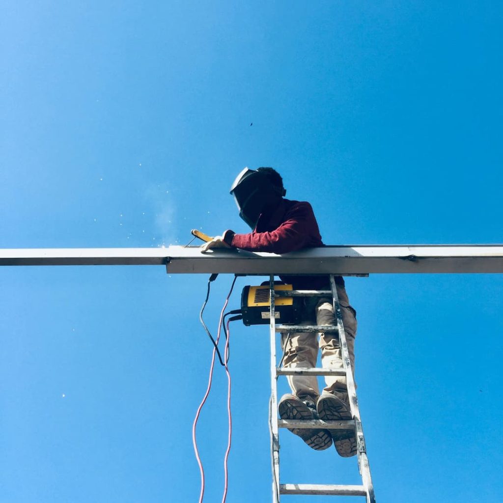 Man working unsafely at a height due to leaning on ladder