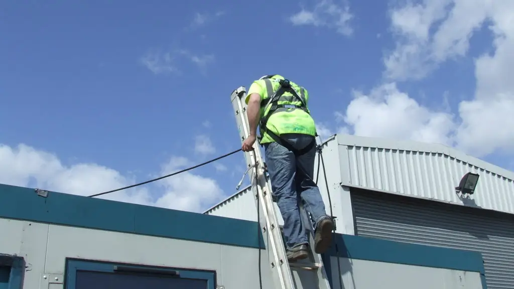 Male on ladder wearing hi vis and height safety harness