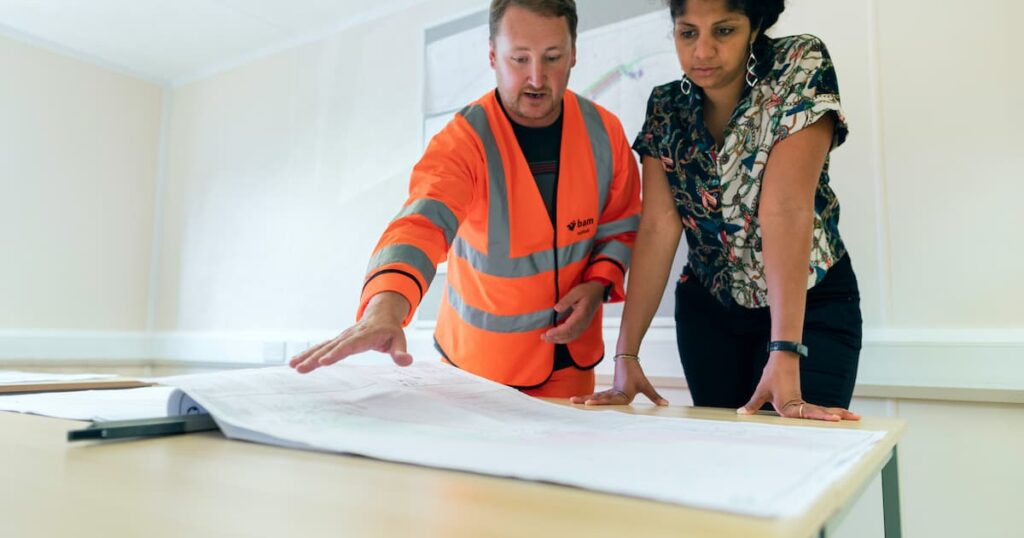 Man wearing orange hi-vis with a corporate women explaining safety plans